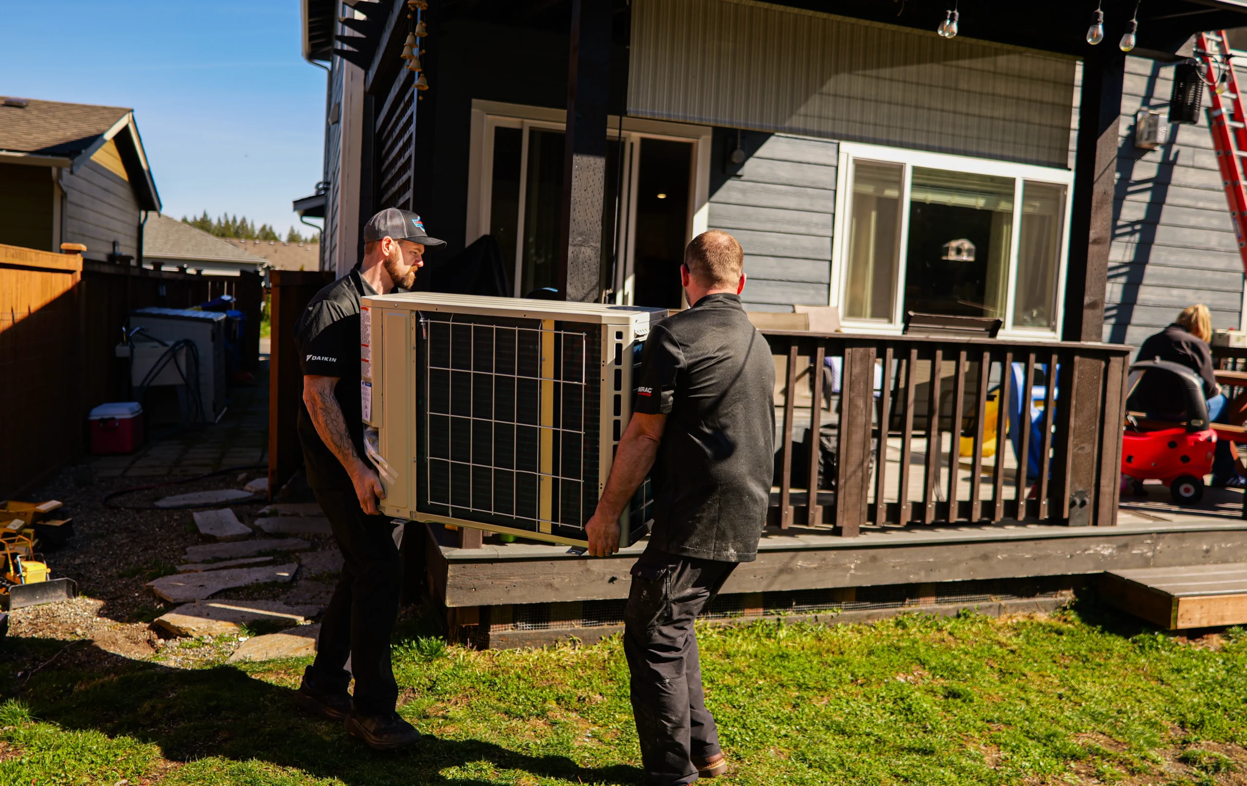 Workers carrying air conditioning unit outdoors
