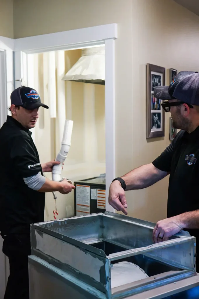 Technicians installing HVAC equipment indoors.
